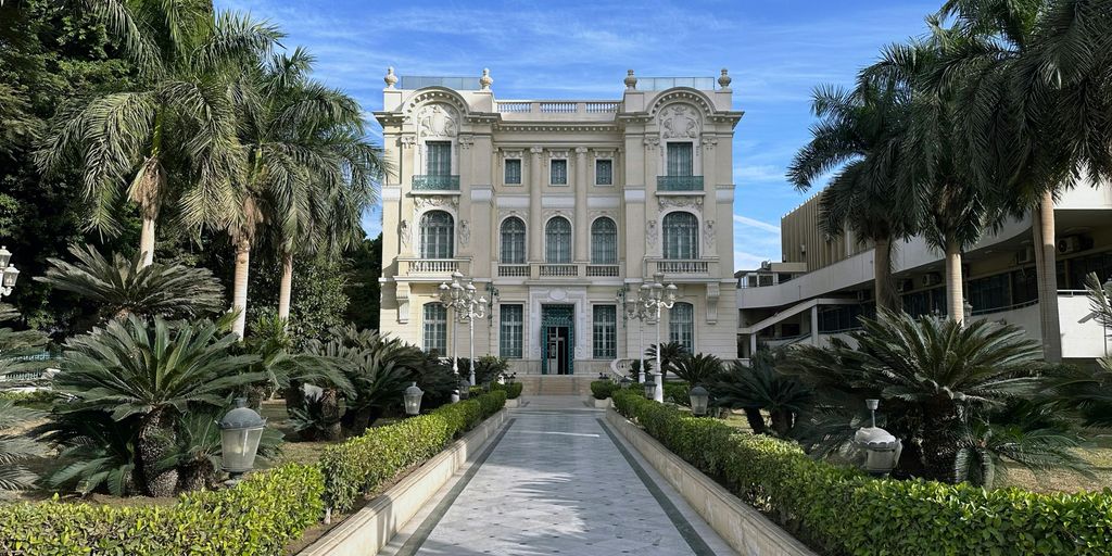 A large white building with a long driveway in front of it